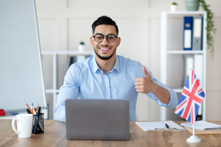 Online tutoring and remote education. Friendly male tutor having video call with students on laptop, showing thumb up, giving lesson on web from home. Young Arab teacher conducting lecture on internet